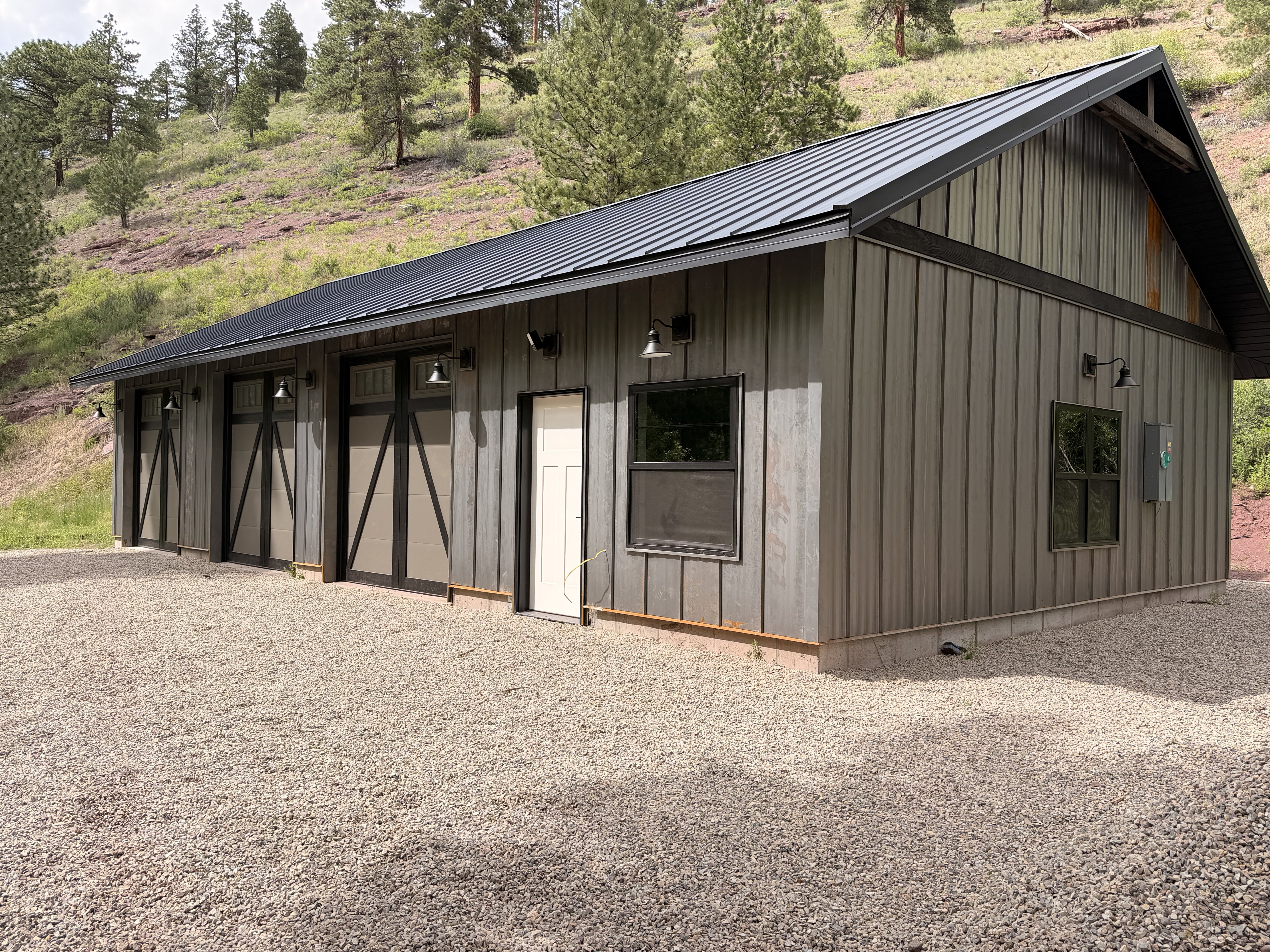Completed outbuilding — metal roof, vertical siding & 3-car garage doors